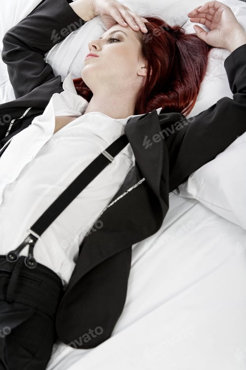 Preview: Professional Business Woman Lying On A Bed After A Long Day In The Office Nursing A Headache.