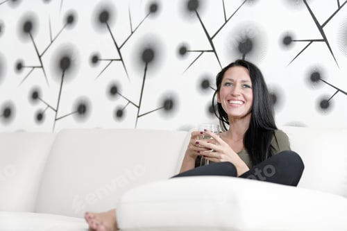 Preview: Attractive Young Woman Relaxing On Her Sofa At Home With A Glass Of White Wine.