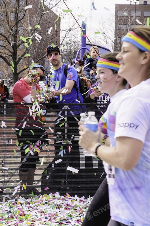 Preview: Kalamazoo, Michigan, Usa - April 12, 2014: Volunteers Blow Colored Confetti At Runners In A 5K "Fun