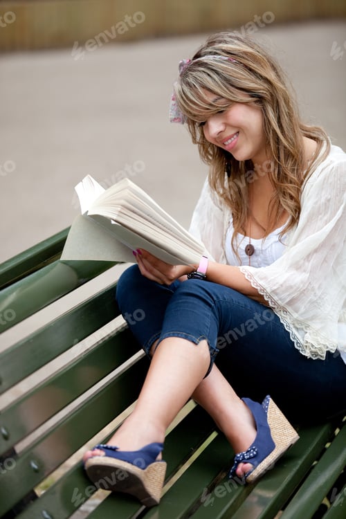Preview: Beautiful Woman Sitting Outdoors In A Bench Reading A Book