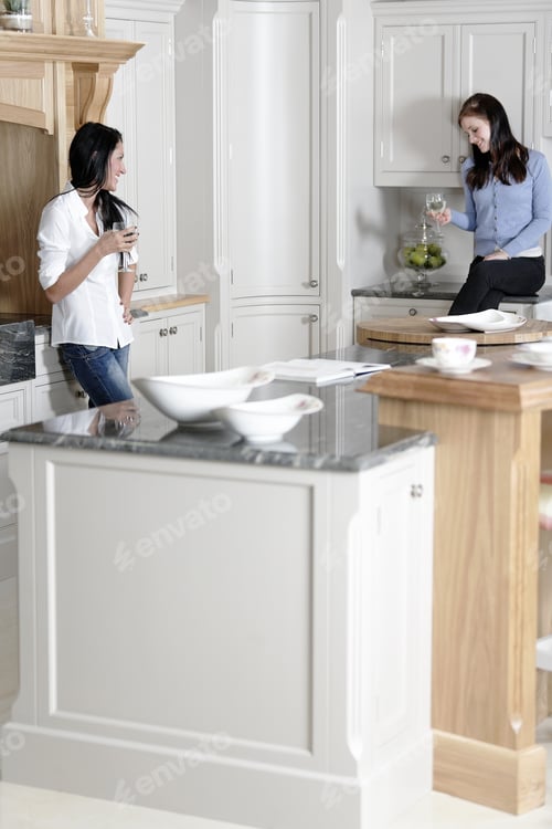 Preview: Two Attractive Young Friends Laughing And Drinking Wine In Their Kitchen.