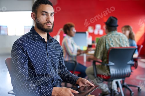 Preview: Confident Male Designer Working On A Digital Tablet In Red Creative Office Space
