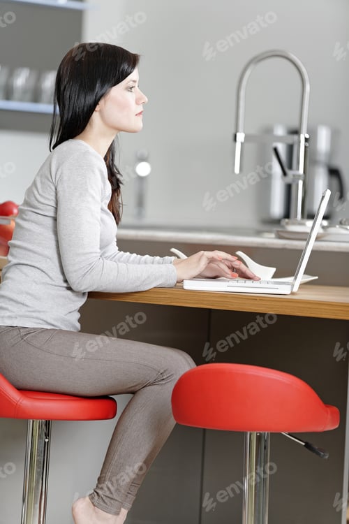 Preview: Attractive Young Woman In Her Elegant Kitchen Taking A Break With Her Laptop