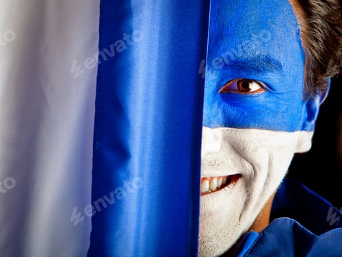 Preview: Man With A Blue And White Flag Painted On His Face - Isolated Over Black