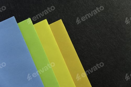 Preview: Corners Of Four Colored Envelopes On Black Cardboard