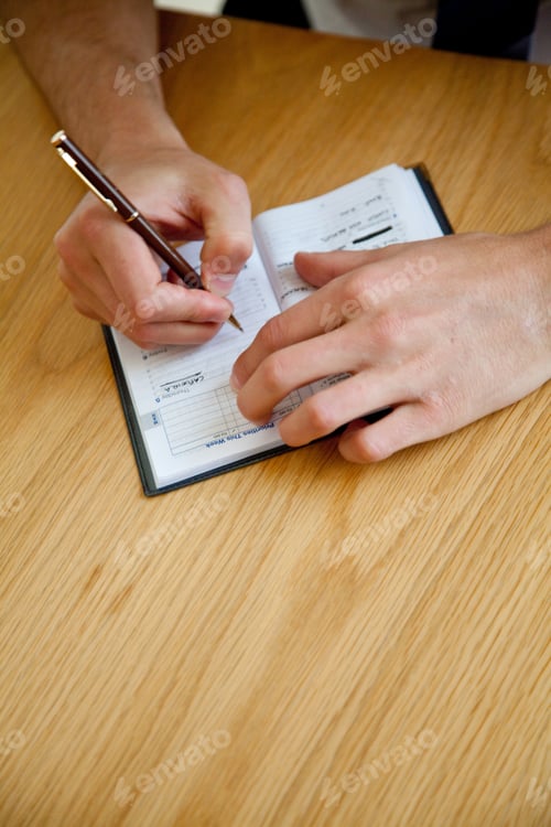 Preview: Business Man Writing An Appointment On His Agenda