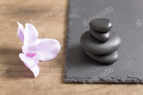 Preview: Pile Of Four Spa Stones With A Fresh Orchid Flower Next To It On A Slate Tray