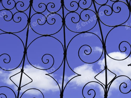 Preview: Detail Of Garden Structure Of Ironwork With Curlicues Between Ribs Against A Blue Sky And A Few