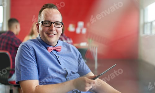 Preview: Confident Male Designer Working On A Digital Tablet In Red Creative Office Space