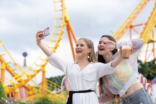 Preview: Two Joyful Cheerful Girls Taking A Selfie At The Amusement Theme Park On Roller Coaster Background