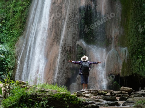 Preview: Senior Man With Backpacks Enjoying Waterfall Raised Hands Travel Lifestyle And Success Concept