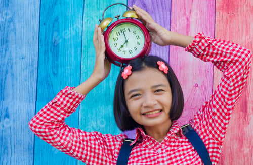 Preview: Asia Young Girl Hold Alarm Clock With Colorful Background.