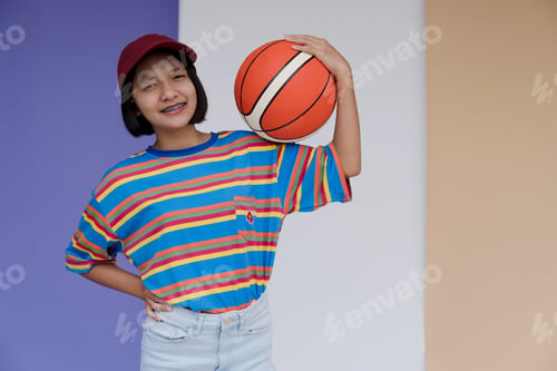 Preview: Happy Young Asian Girl Palying Basketball With Pastel Background.
