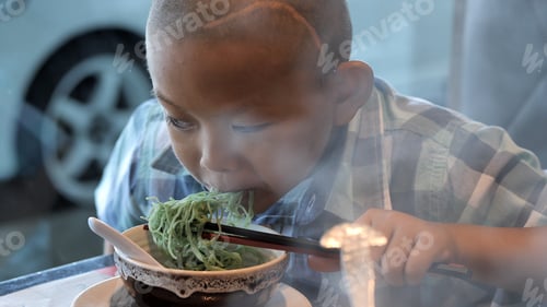 Visualização: Criança feliz comendo macarrão delicioso no restaurante. Meninos asiáticos com deficiências visuais. Esquerda