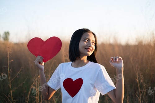 Preview: Happy Asian Girl Hold A Red Paper Heart At Brown Grass Sunset Time.