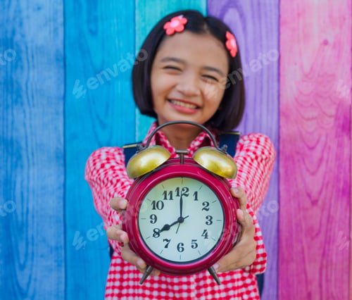 Preview: Asia Young Girl Hold Alarm Clock With Colorful Background.