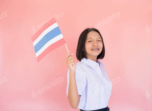 Preview: Portrait Asian Young Girl Hold Thai Flag With Pink Background In Student Uniform.
