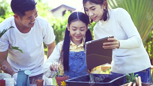 Preview: Parent And Daughter Planting Tree In Garden At Home. Family Lifestyle On Summer Holiday.