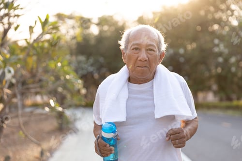 Preview: Front View Asian Elderly Exercise. Close Up Senior Man Holding Water Bottle Running On Road In