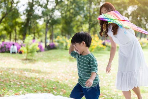 Preview: Happy Cheerful Asian Little Boy Running And Playing With Kite Flying With Mother Outdoor In The
