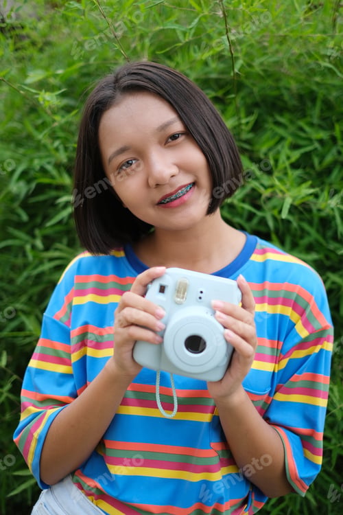 Preview: Happy Young Asian Girl With Blue Camera And Nature Background.