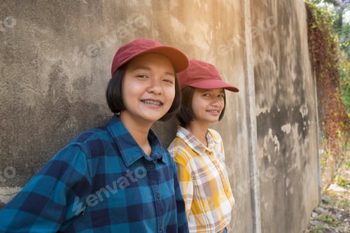Preview: Happy Two Asian Girl Wear Red Hat With Old Wall Background At School.