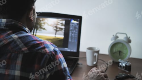 Preview: Back View Of Male Photographer Working At Home On Laptop, Retouching Photos
