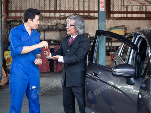 Aperçu: Concept de garagiste. Le mécanicien communique avec le client au centre de service automobile.