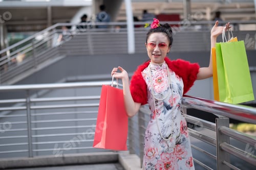 Preview: Young Asian Woman In Chinese Dress Holding Shopping Bags In City Centre Bangkok, Thailand. Chinese