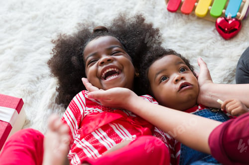 Preview: Cheerful Cute African American Little Smiling Girl And Little Boy Having Fun On Floor At Home