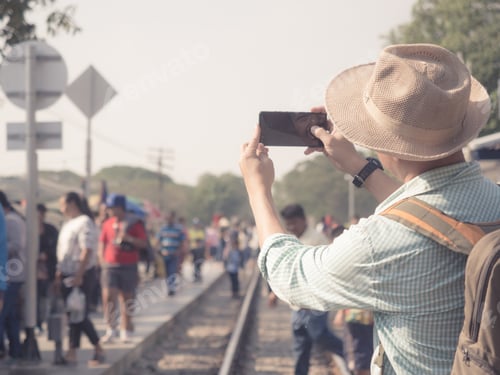 Visualização: Conceito de viagem. Bonito homem asiático usa chapéu com turista em fundo ferroviário. Viajante tire uma foto de