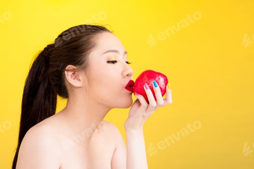 Preview: Beautiful Young Asian Woman Portrait Kissing Red Apple Isolated On Yellow Background. Half Naked