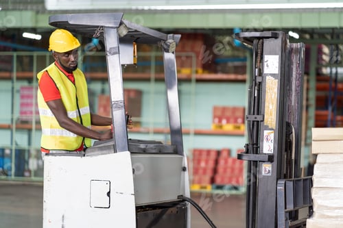 Preview: African American Male Warehouse Worker In Safety Vest And Helmet Driving And Operating On Forklift