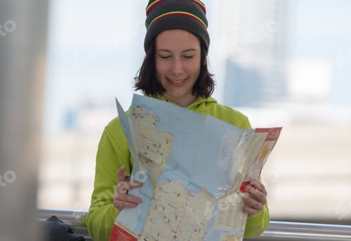 Preview: Happy Female Tourist With Suitcase Exploring Map While Standing In City Building