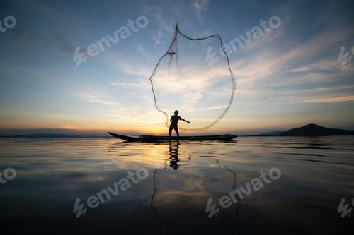 Preview: Asian Fishermen On Wooden Boat For Catching Freshwater Fish In Nature River At Before Sunset Is A