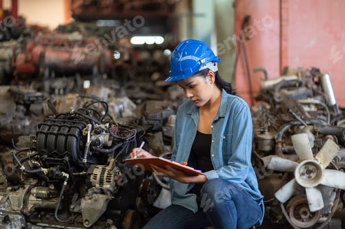 Preview: Asian Female Worker In Helmet Working With Clipboard And Checking Old Automotive Spare Parts