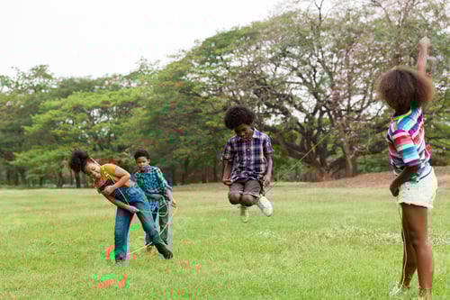 Preview: Group Of African American Children Having Fun Jumping Over The Rope In The Park. Cheerful Kid