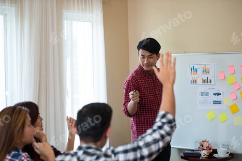 Preview: Young Asian Men Wearing Casual Plaid Shirt Standing In Front Of The Room Is Asking For Feedback