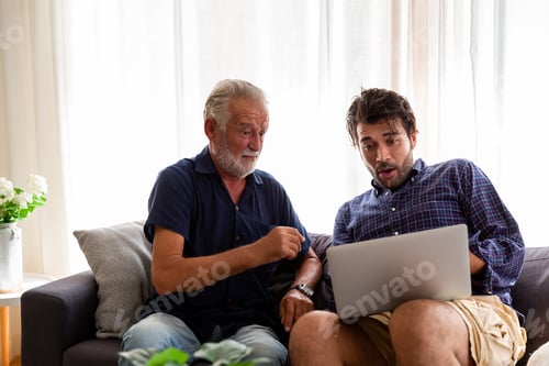 Preview: Senior Father And Adult Son Using Laptop At Home.