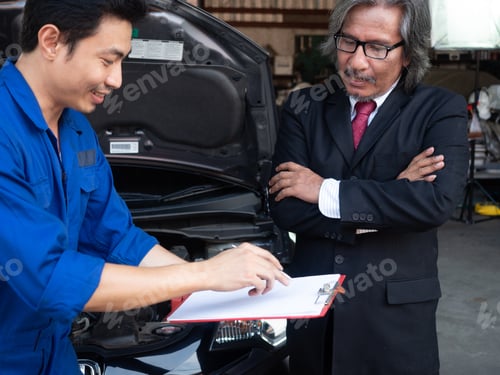 Aperçu: Concept de garagiste. Le mécanicien communique avec le client au centre de service automobile.