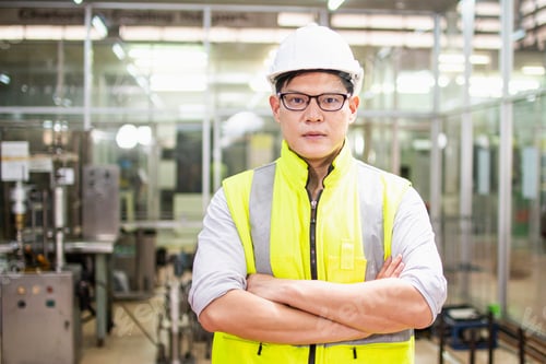 Preview: Smart Asia Engineer Man Standing With Cross Arms At The Camera With An Industrial Plant In The