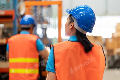 Preview: Asian Young Female Employee Warehouse Worker With Safety Vest And Helmet Using Clipboard For