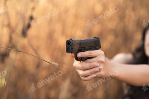 Preview: Beautiful Asian Women Aim The Gun On Dry Grass Background
