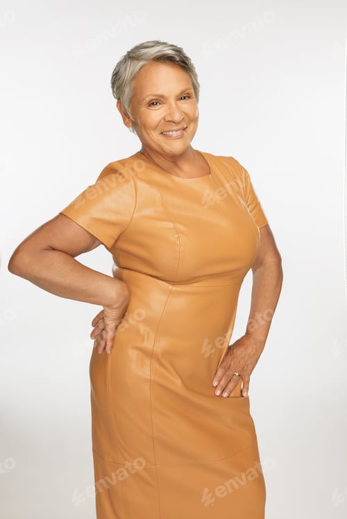 Preview: Three Quarter Length Shot Of Beautiful Hispanic Woman In Her 60S Smiling And Wearing An Orange