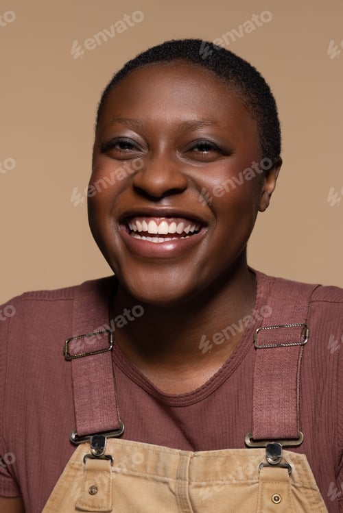 Preview: Portrait Of A Non-Binary Afro-Latino In Their 20'S Smiling On A Neutral Background.