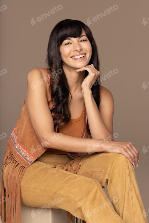 Preview: Studio Portrait Of Beautiful Native American Woman In Her 30S Sitting And Smiling On Neutral