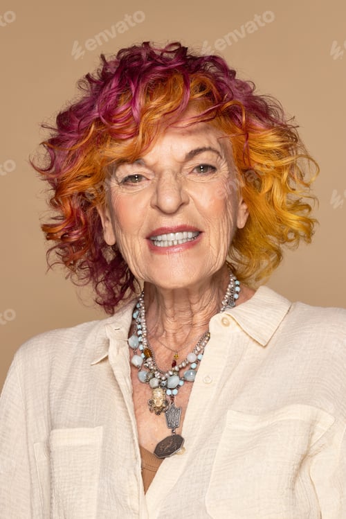 Preview: Portrait Of Beautiful Caucasian Woman With Colorful Hair In Her 70S Posing Confidently On Neutral