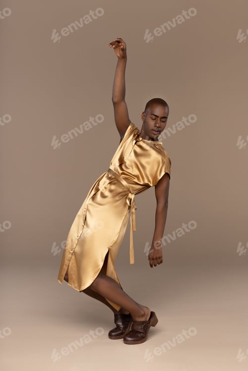 Preview: Young Bald African Man In His 20S Wearing Golden Tunic Posing Expressively On A Neutral Background