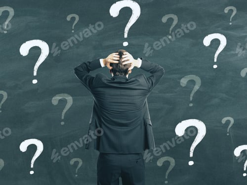 Preview: Back View Of Young Businessman On Chalkboard Wall Background With Question Marks. Confusion And