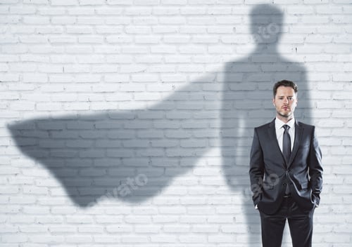 Preview: European Businessman With Super Hero Cape Shadow Standing On Brick Wall Background. Leadership And